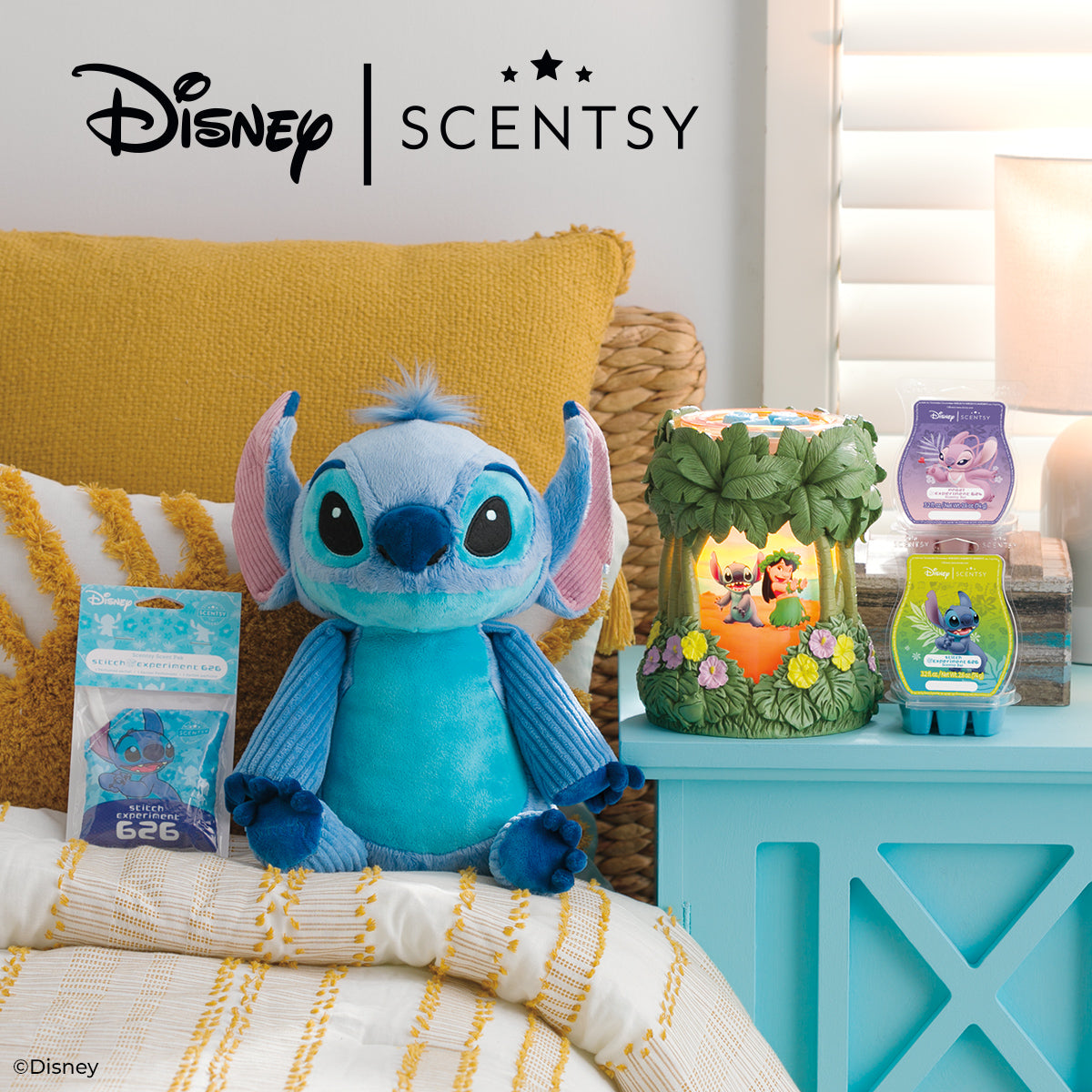 Disney Scentsy products including a plush toy and candles on a table with a yellow cushion in the background.