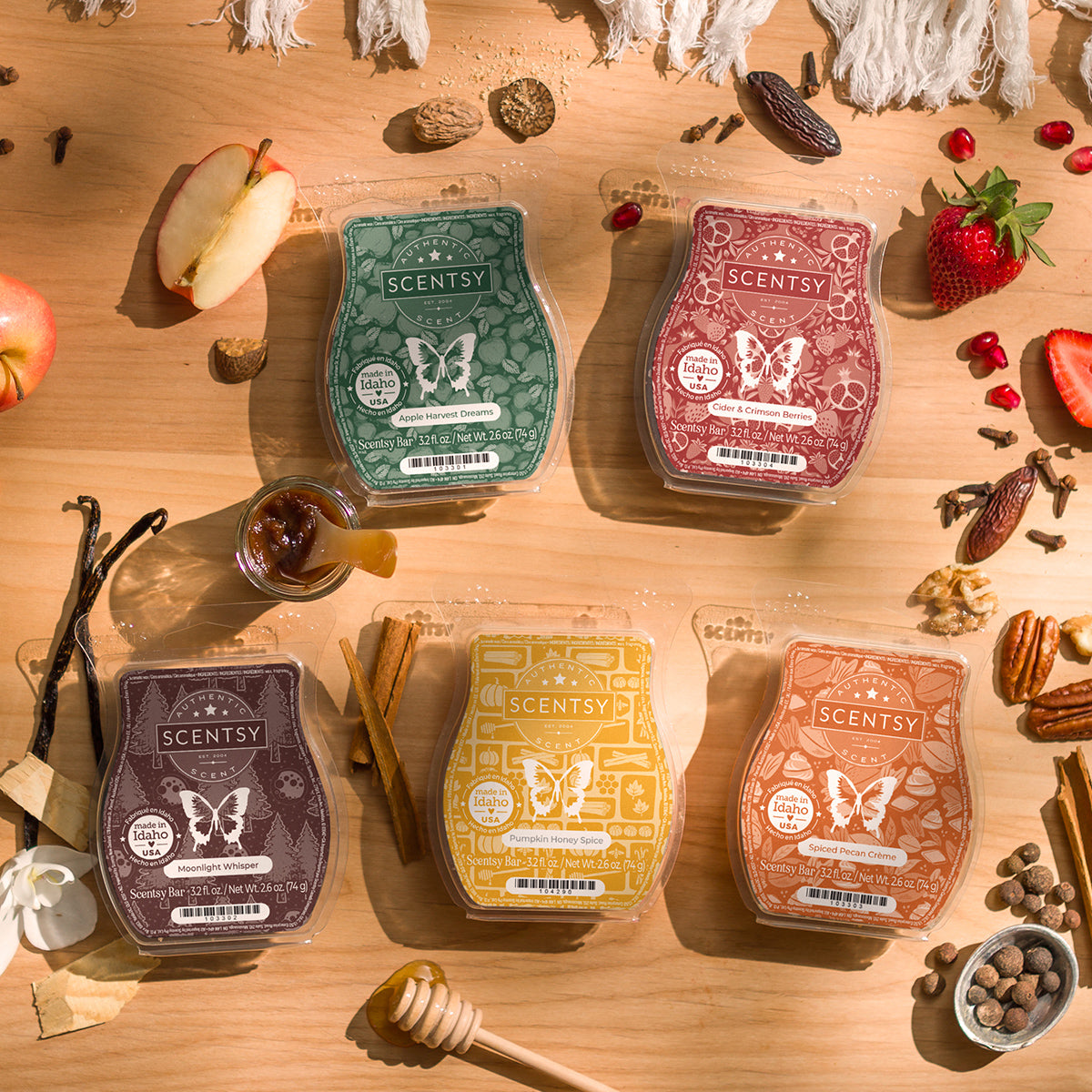 Five Scentsy wax melts on a wooden surface with various spices and fruits.
