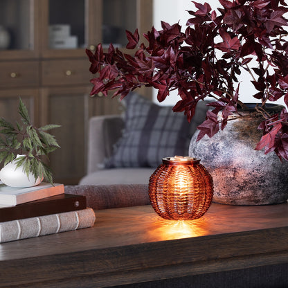 Decorative candle holder on a wooden surface with plants and books in the background