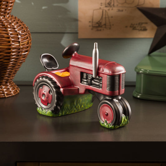 Red tractor figurine on a dark surface with a wicker basket and green container in the background.