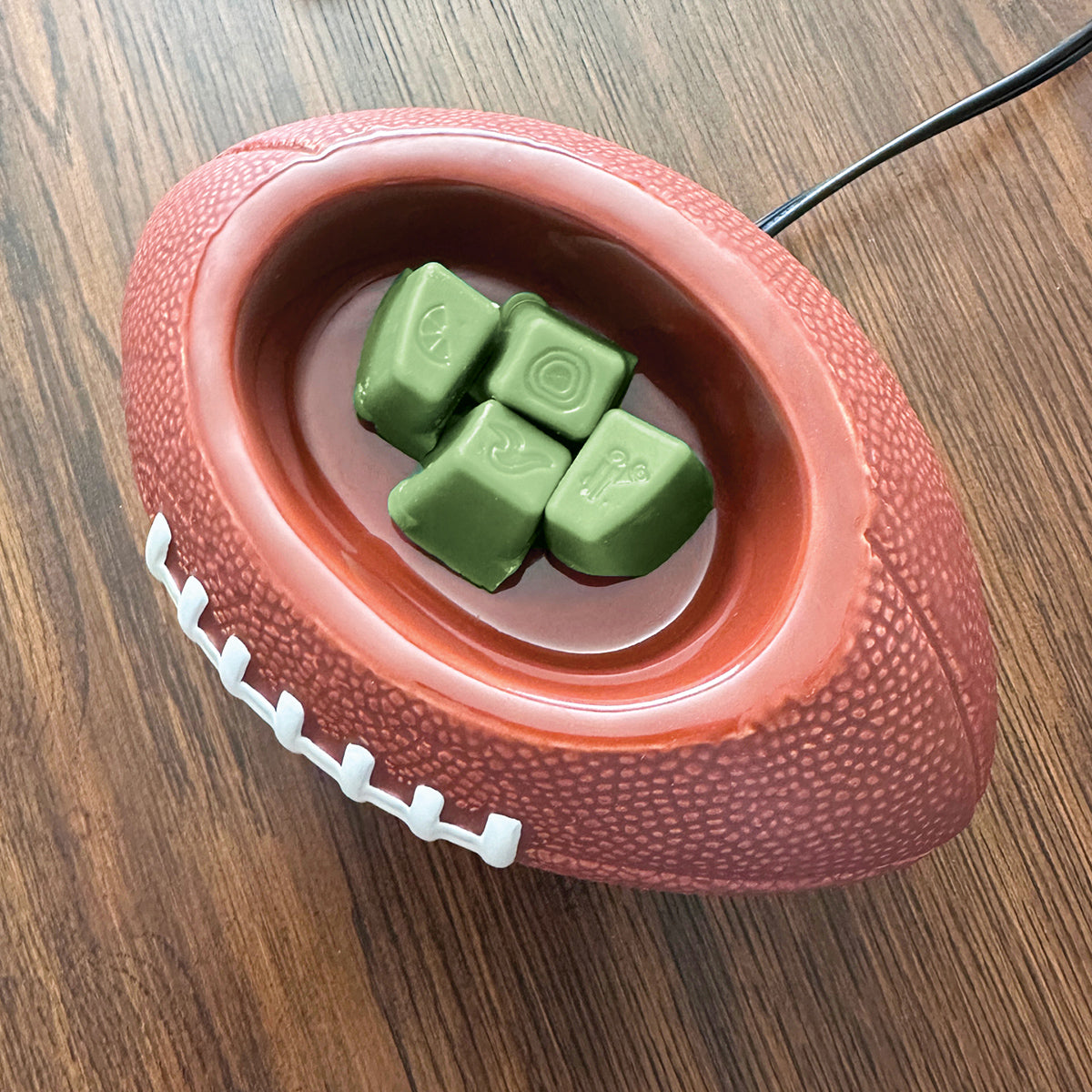 Red football-shaped pet toy with green treats on a wooden surface