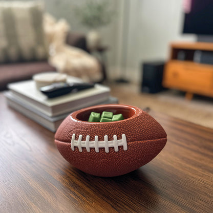 Football-shaped container with snacks on a wooden table in a living room setting