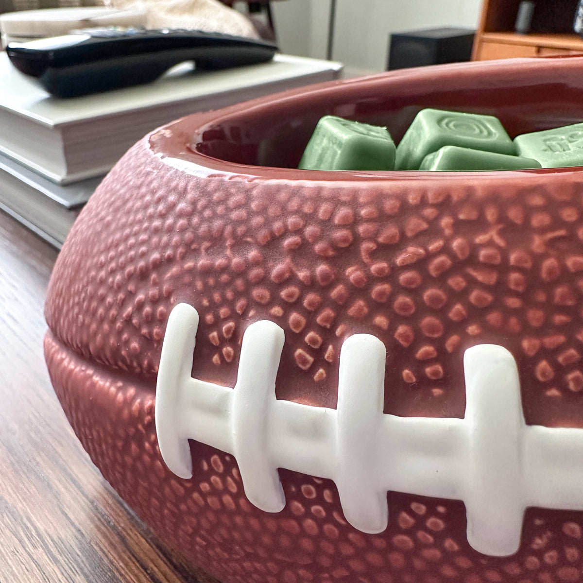 Football-shaped bowl with green treats on a wooden surface