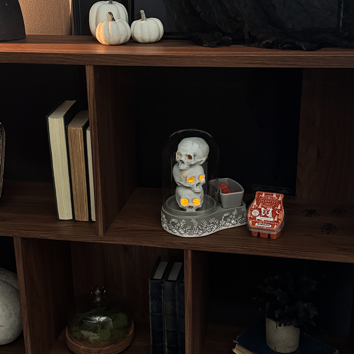 Decorative shelf with Halloween-themed items including a skeleton figure and pumpkins.