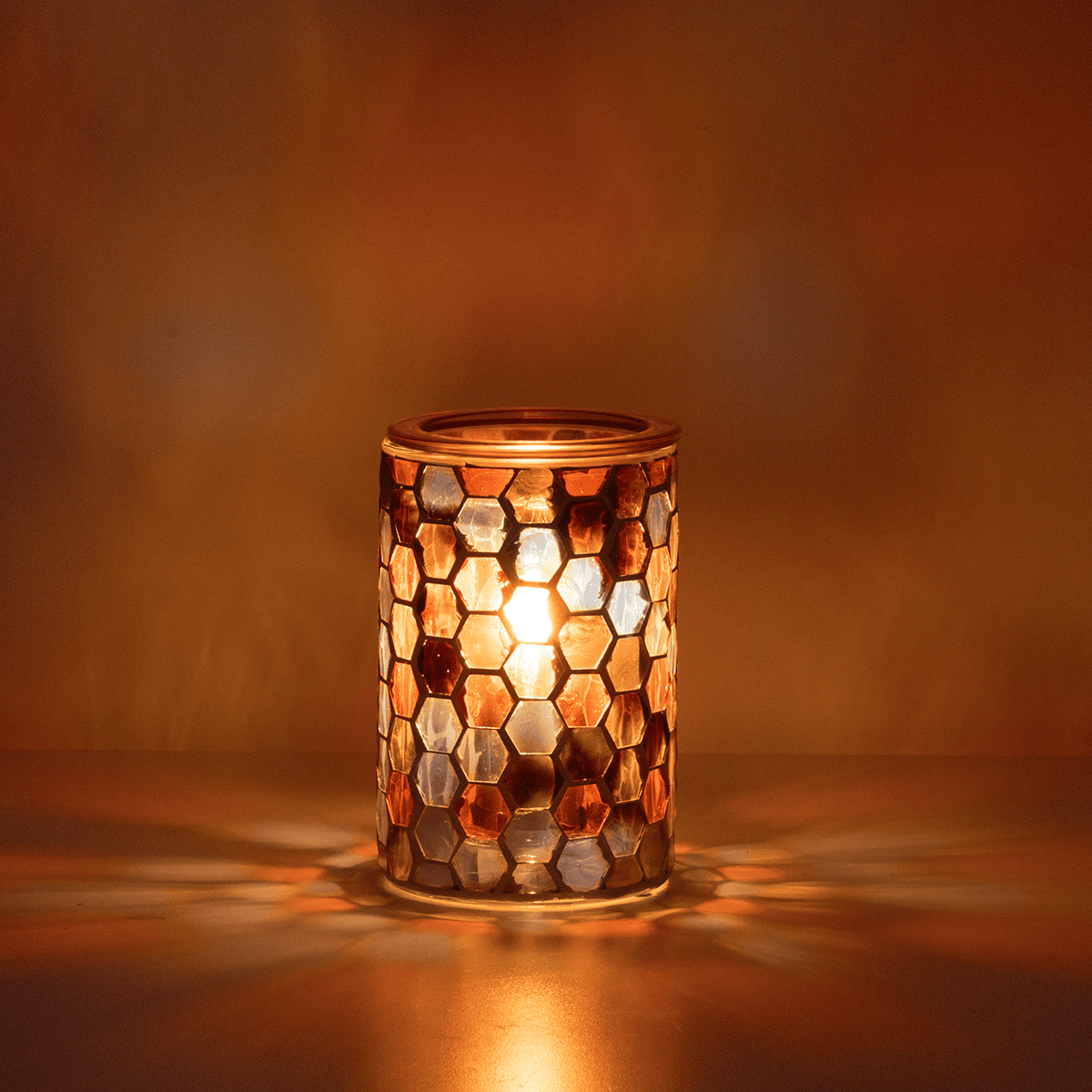 Mosaic candle holder with a warm glow on a brown background