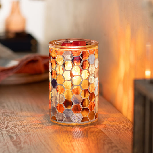 Mosaic-patterned candle holder on a wooden surface with warm lighting