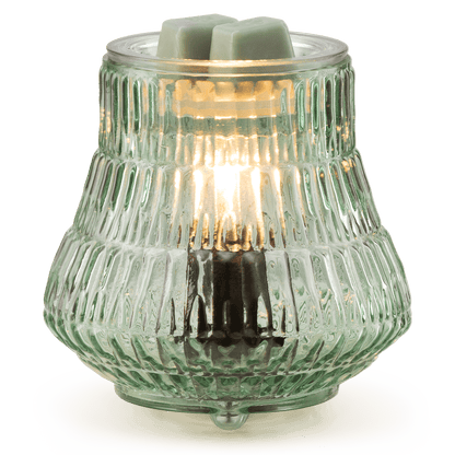 Decorative glass lamp with a light bulb inside on a white base against a green background