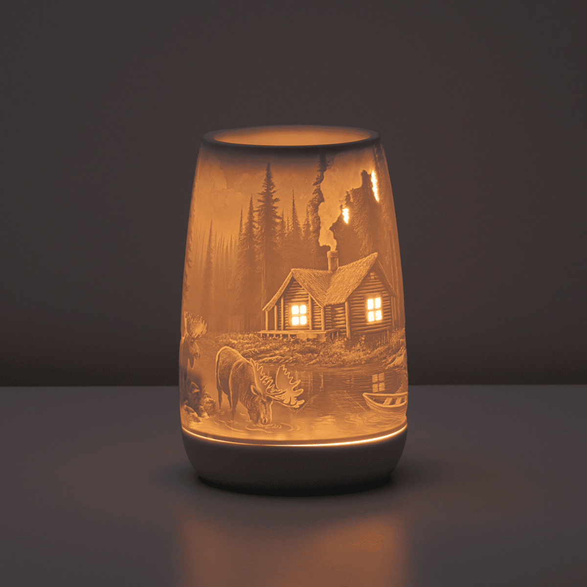 Decorative lamp with engraved scene of a cabin and nature on a dark background