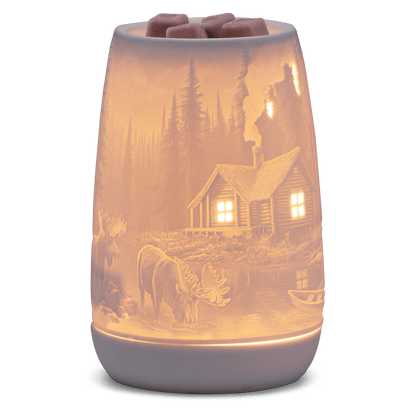 Wax warmer with a scenic design of a cabin and nature on a white background
