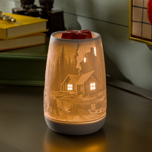 Decorative lamp with engraved cabin design on a table