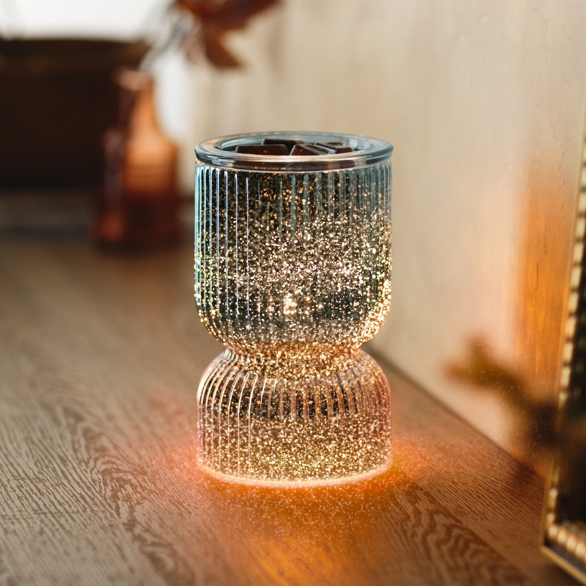 Decorative glass lantern with a warm glow on a wooden surface