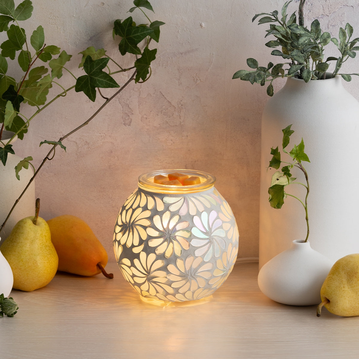 Decorative lamp with floral pattern on a table with pears and vases.