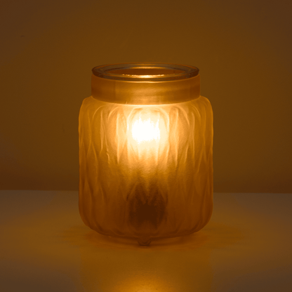 Glass candle holder with a warm glow against a dark background