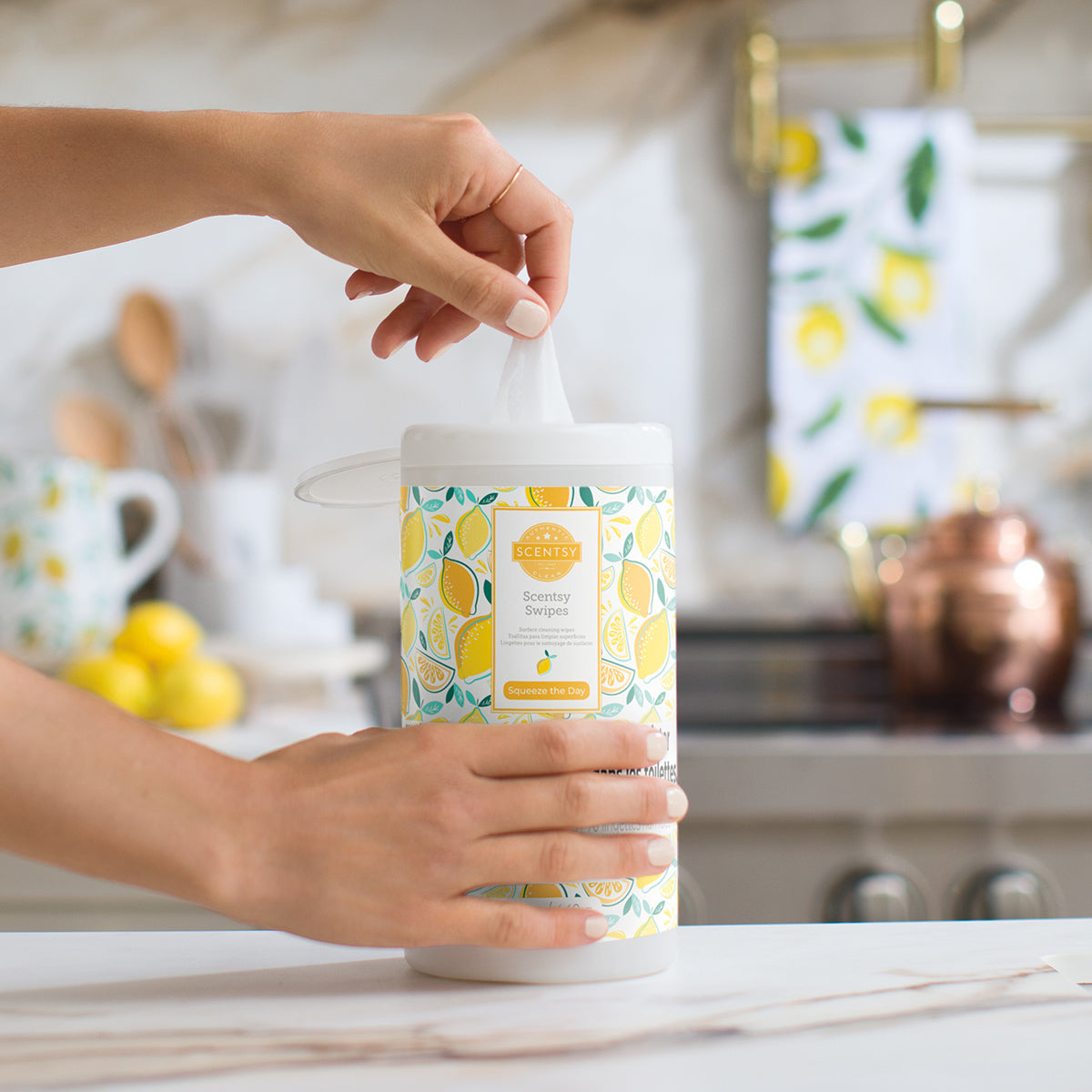 Person holding a lemon-themed candle in a kitchen setting