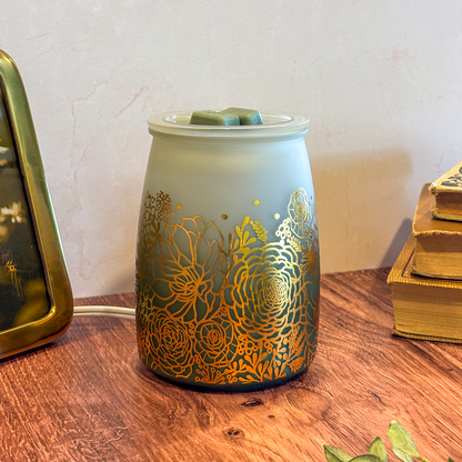 Decorative wax warmer with gold floral patterns on a wooden surface