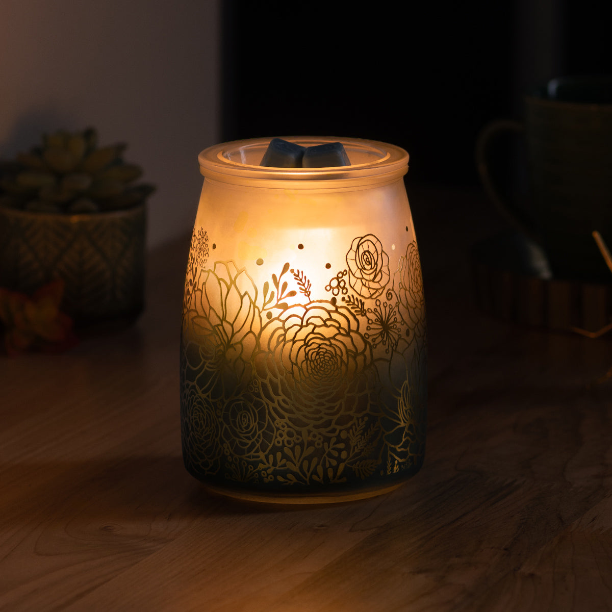 Decorative candle warmer with floral patterns on a wooden surface